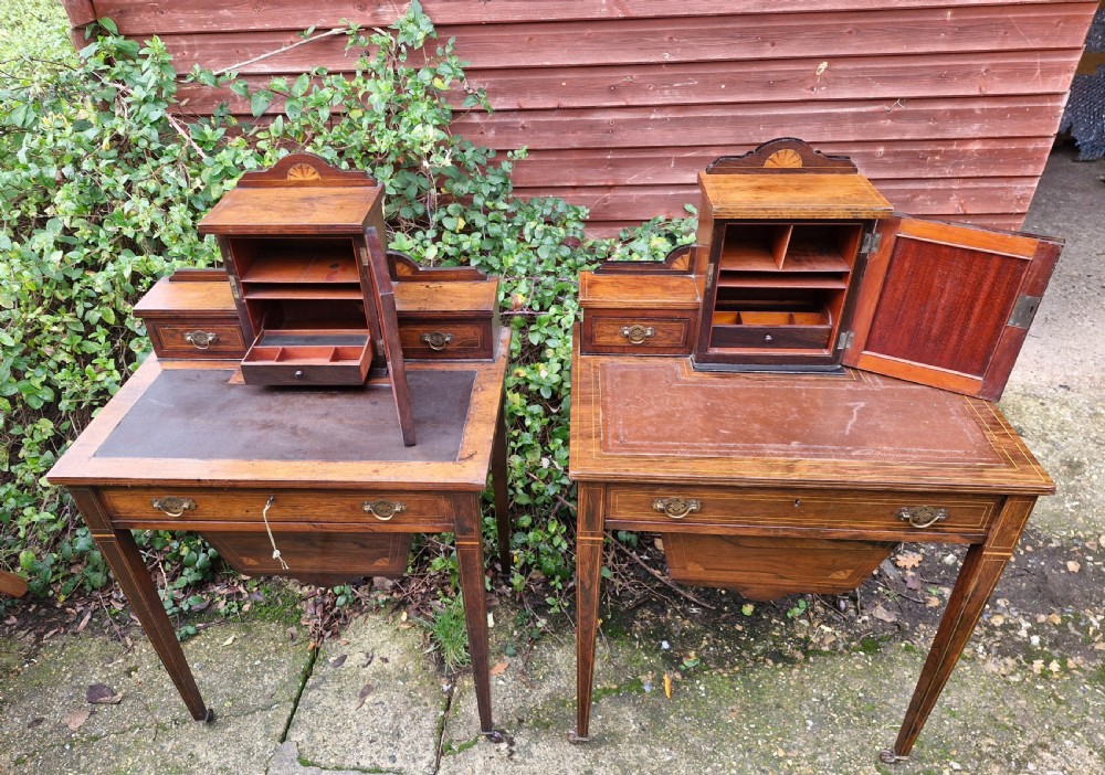 A pair of late Victorian rosewood writing tables featuring central raised cupboards with urn inlay, leather surfaces, and tapered square legs. View X