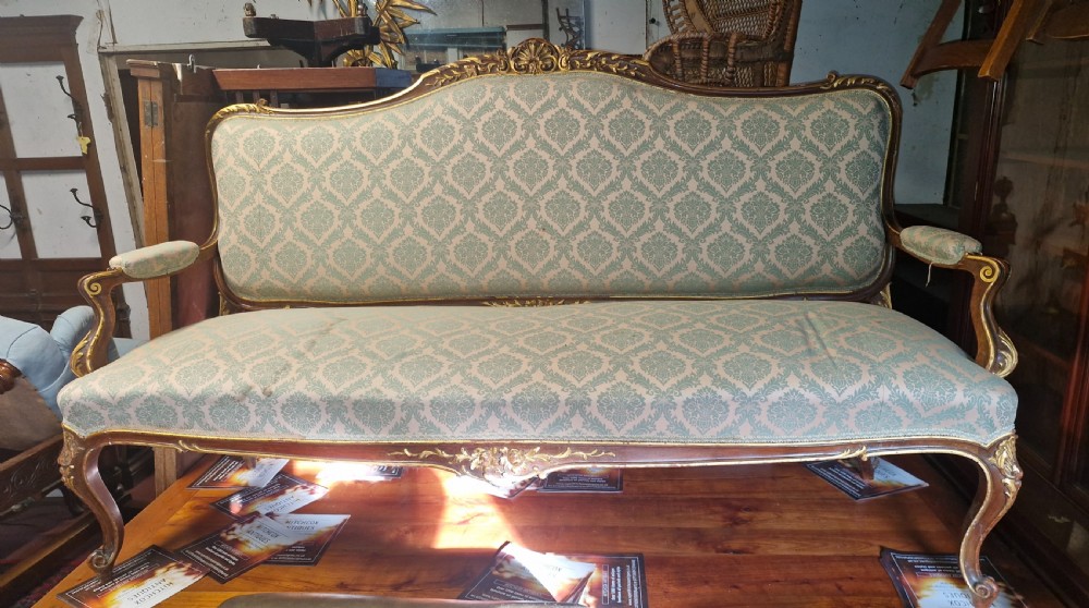 Carved and gilt heightened open arm sofa.