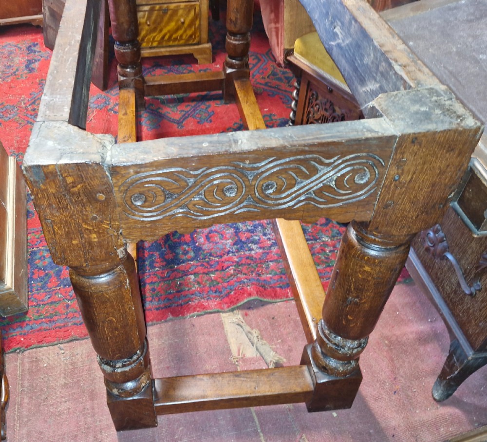 A rectangular dark oak refectory-style serving table featuring a carved frieze apron, turned legs, and a low box stretcher. View XI