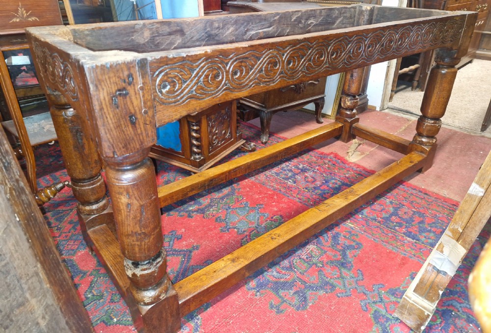 A rectangular dark oak refectory-style serving table featuring a carved frieze apron, turned legs, and a low box stretcher. View XIII
