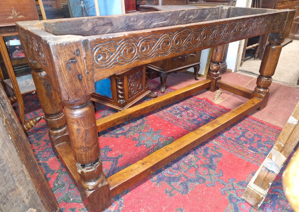 A rectangular dark oak refectory-style serving table featuring a carved frieze apron, turned legs, and a low box stretcher. View XIV