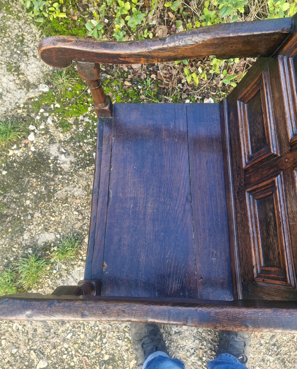 An early 18th-century dark oak wainscot armchair featuring a pierced carved cresting rail, four recessed geometric back panels, curved armrests, and turned front legs. View XI