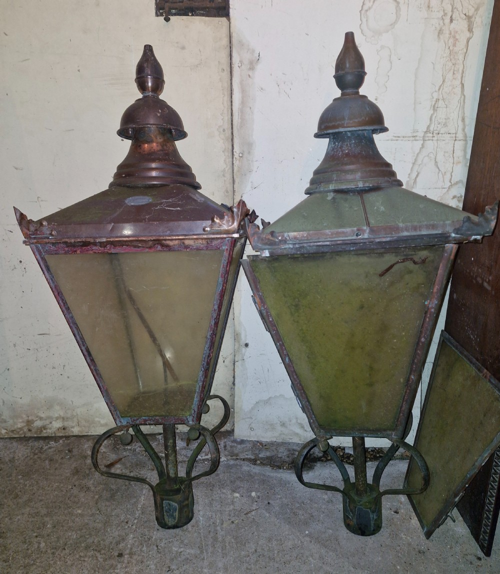 A pair of antique copper street lantern tops featuring tapered glazed panels, decorative finials, and scrolled iron mounts. View II