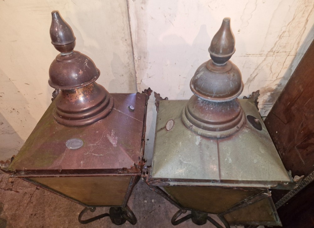 A pair of antique copper street lantern tops featuring tapered glazed panels, decorative finials, and scrolled iron mounts. View III