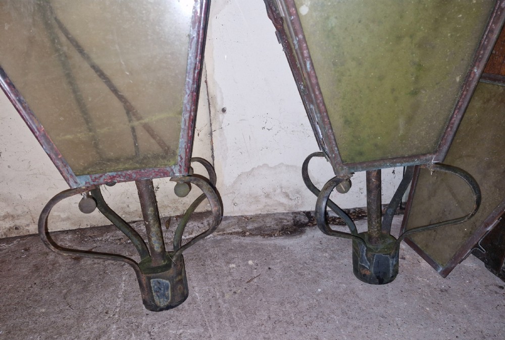 A pair of antique copper street lantern tops featuring tapered glazed panels, decorative finials, and scrolled iron mounts. View VI