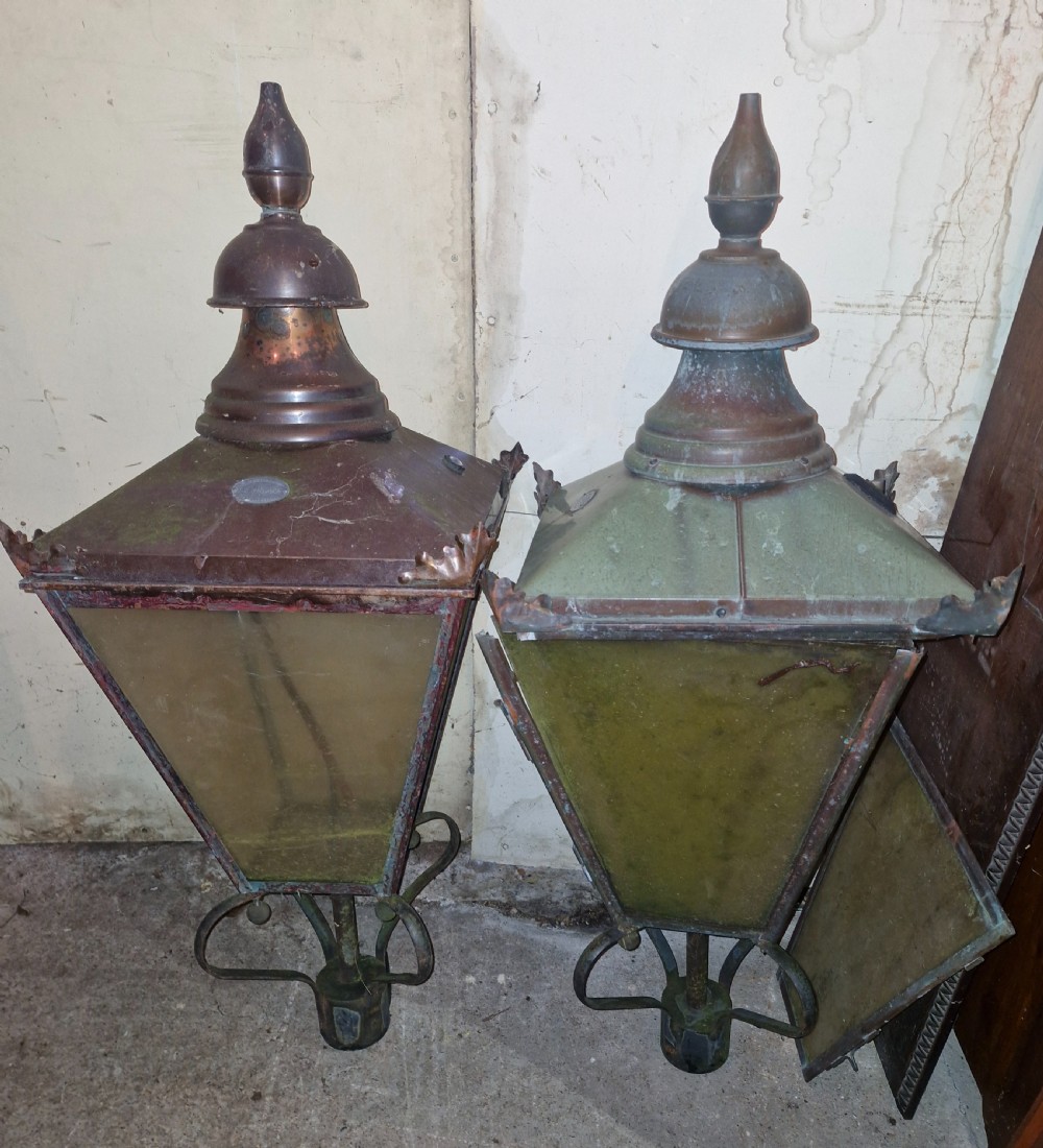 A pair of antique copper street lantern tops featuring tapered glazed panels, decorative finials, and scrolled iron mounts. View VII