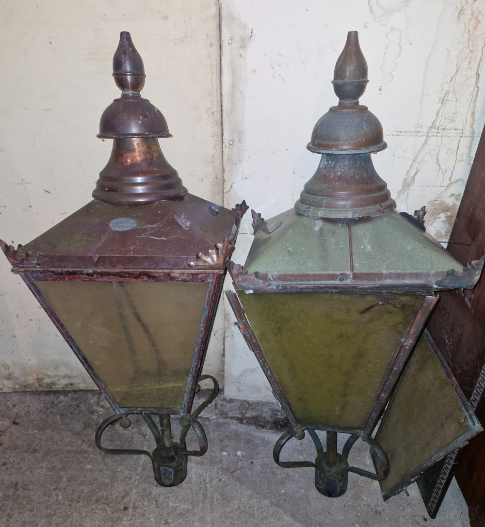 A pair of antique copper street lantern tops featuring tapered glazed panels, decorative finials, and scrolled iron mounts. View VIII