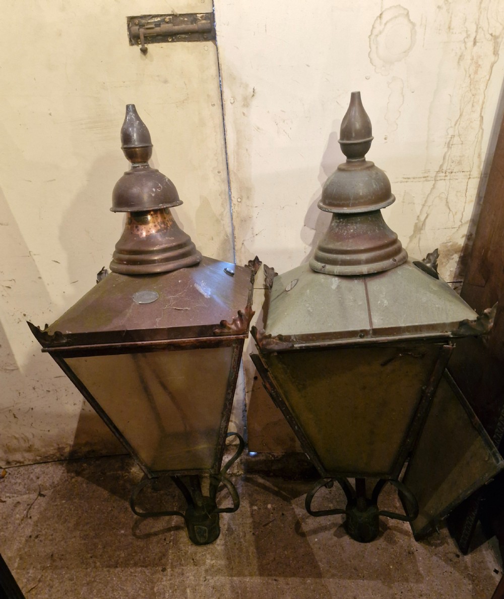 A pair of antique copper street lantern tops featuring tapered glazed panels, decorative finials, and scrolled iron mounts. View IX