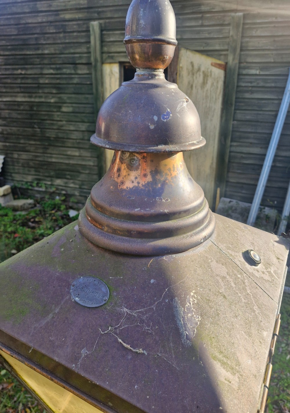 A pair of antique copper street lantern tops featuring tapered glazed panels, decorative finials, and scrolled iron mounts. View X