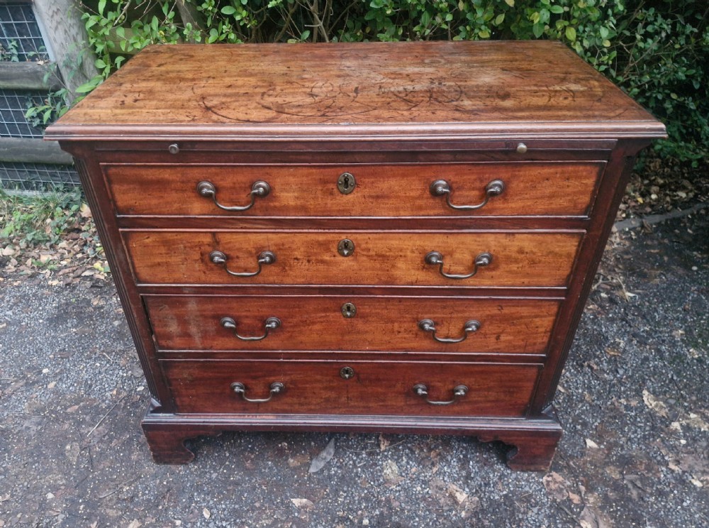 A Georgian mahogany bachelors chest featuring four drawers, a pull-out brushing slide, brass swan-neck handles, and bracket feet.