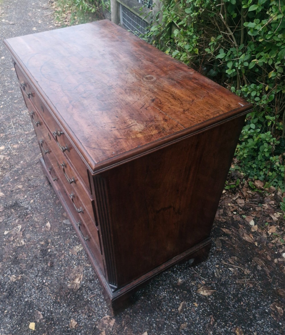 A Georgian mahogany bachelors chest featuring four drawers, a pull-out brushing slide, brass swan-neck handles, and bracket feet. View V