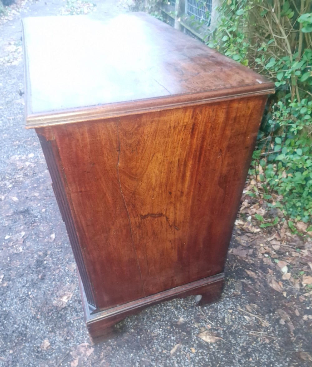 A Georgian mahogany bachelors chest featuring four drawers, a pull-out brushing slide, brass swan-neck handles, and bracket feet. View X