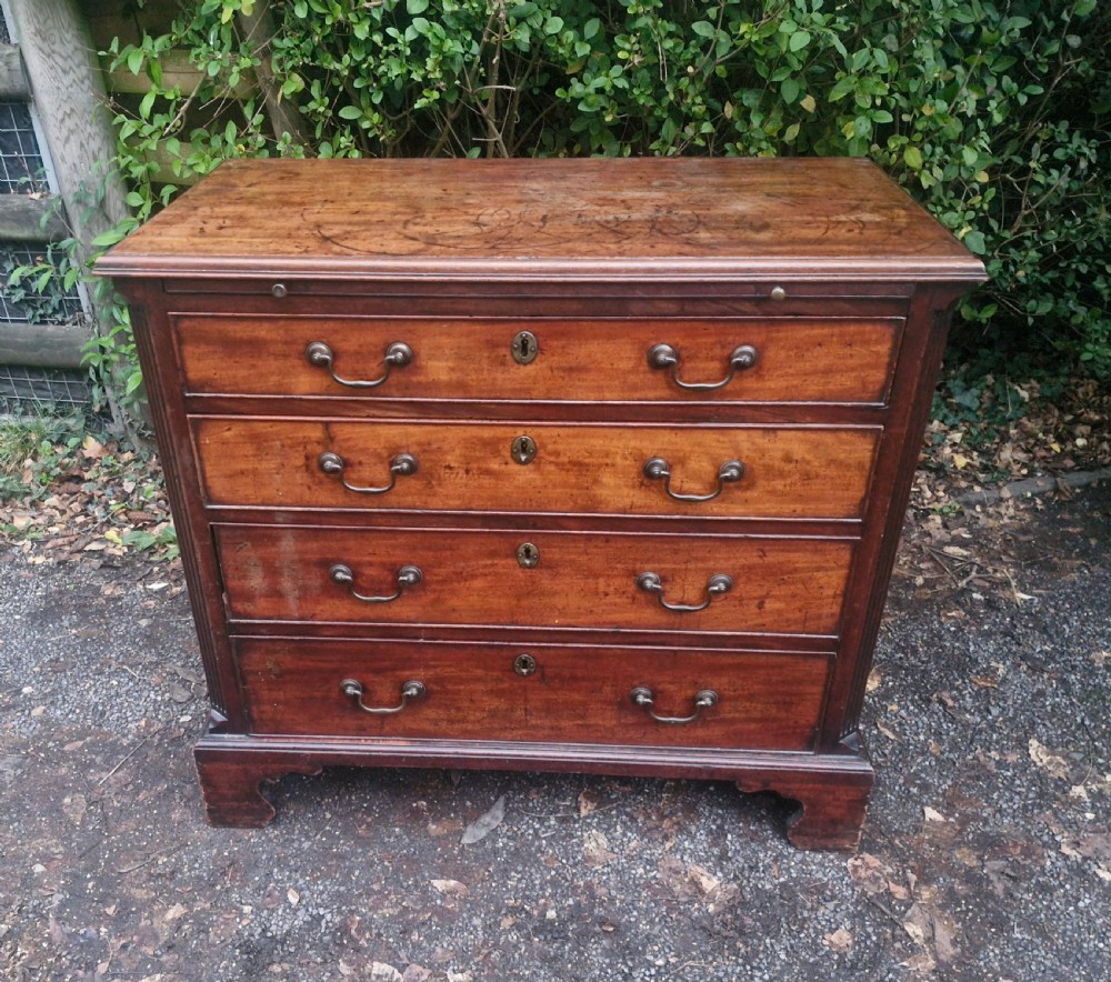 A Georgian mahogany bachelors chest featuring four drawers, a pull-out brushing slide, brass swan-neck handles, and bracket feet. View XV