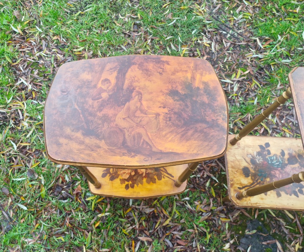 A pair of two-tier rectangular occasional tables featuring gold-painted turned legs, painted figurative scenes on the top surfaces, and floral artwork on the lower shelves. View V