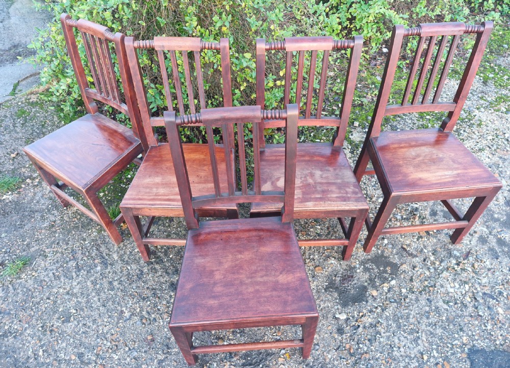 A set of five early Victorian dark-stained timber dining chairs featuring vertical slat backs, turned top rails, solid wooden seats, and straight legs with stretchers. View V