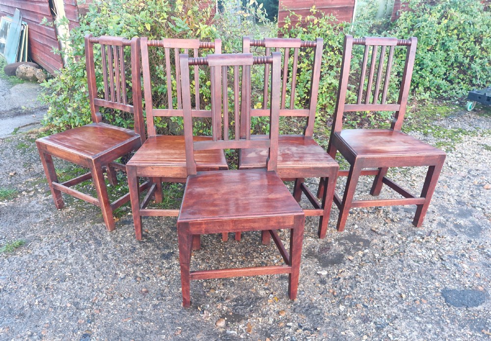 A set of five early Victorian dark-stained timber dining chairs featuring vertical slat backs, turned top rails, solid wooden seats, and straight legs with stretchers. View VI