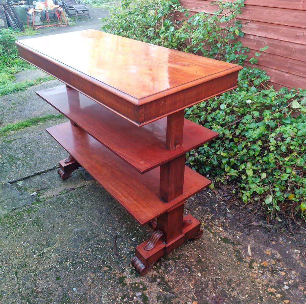 A tiered mid Victorian adjustable dumb waiter crafted from polished mahogany with scrolled feet.