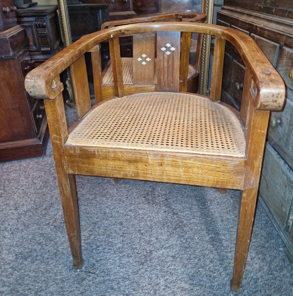 A pair of Anglo Indian Art Deco teak armchairs featuring curved horseshoe backrests with diamond inlay and woven cane seats. View II