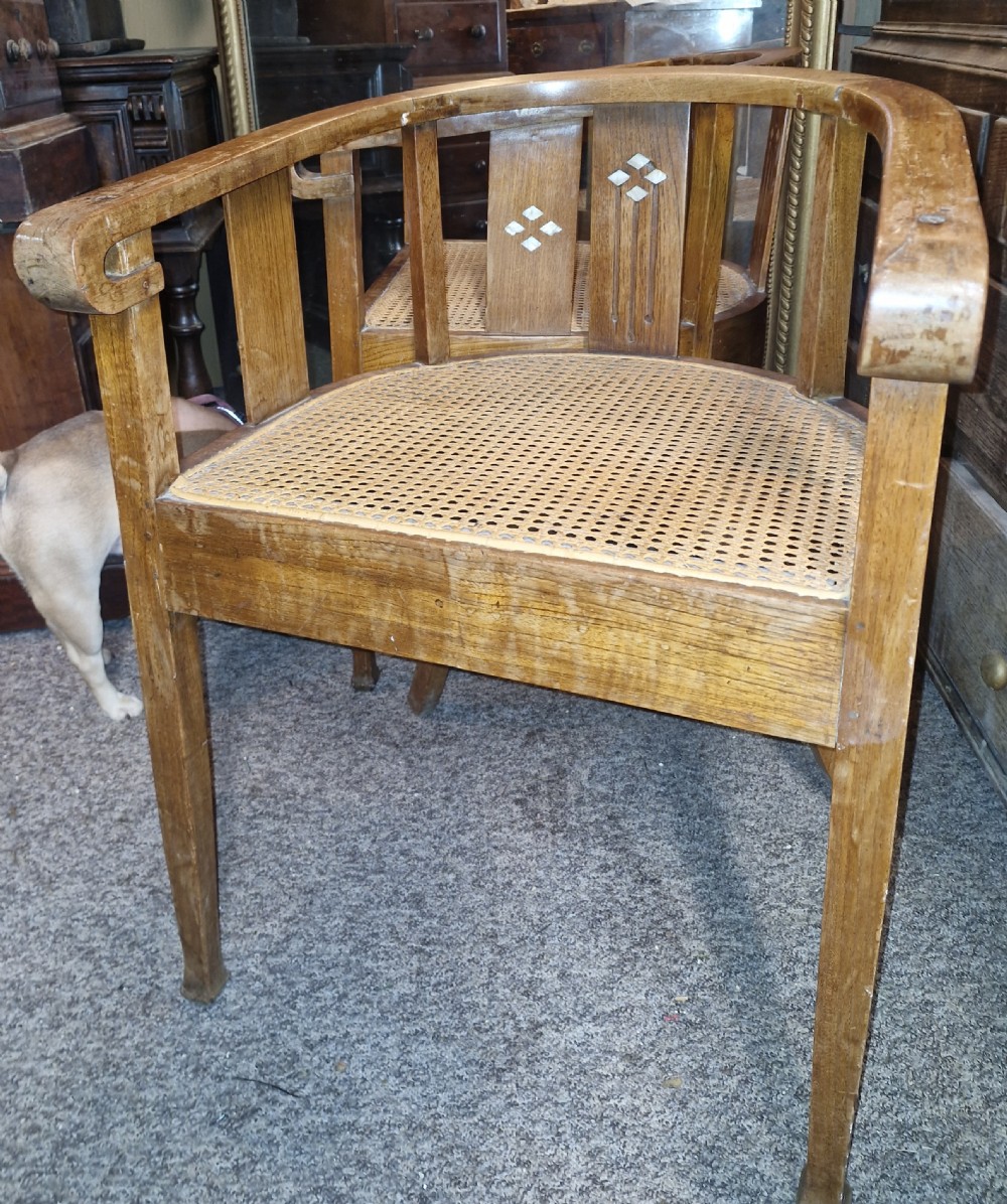 A pair of Anglo Indian Art Deco teak armchairs featuring curved horseshoe backrests with diamond inlay and woven cane seats. View III