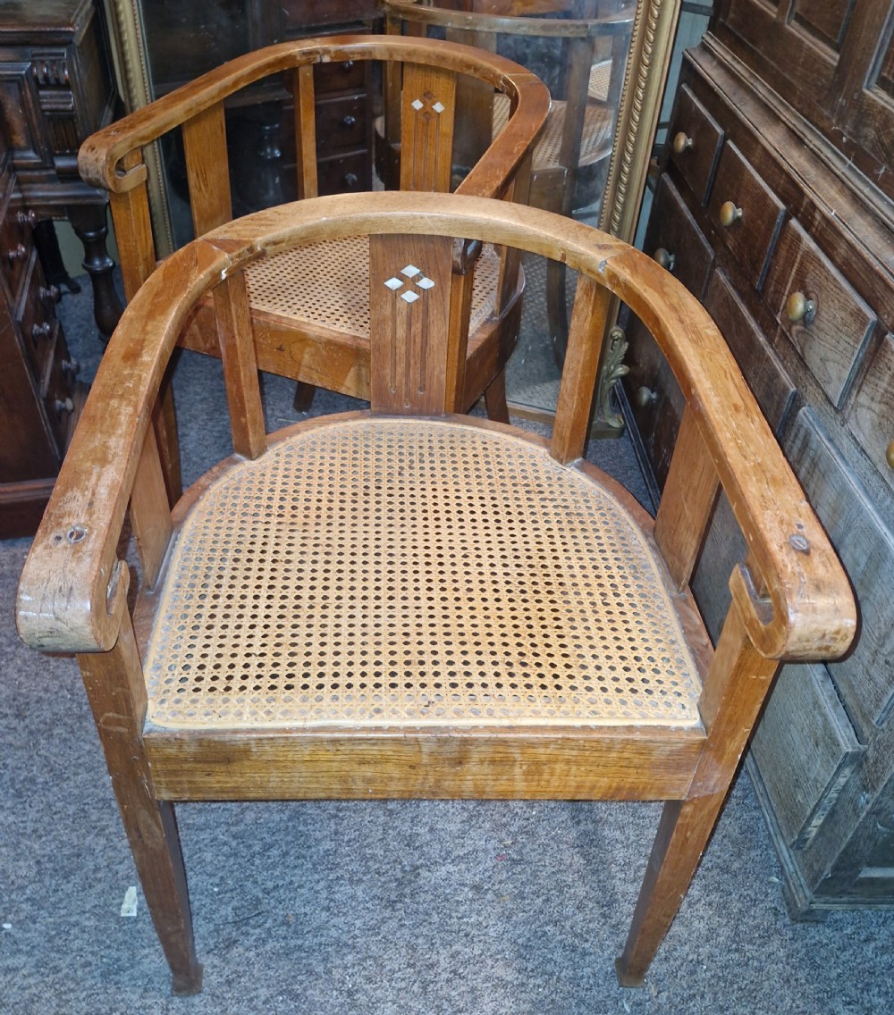 A pair of Anglo Indian Art Deco teak armchairs featuring curved horseshoe backrests with diamond inlay and woven cane seats. View V