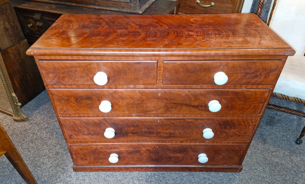 A Victorian pine chest of drawers featuring a warm brown scumbled faux-grain painted finish, two short drawers over three long drawers, and white turned handles.