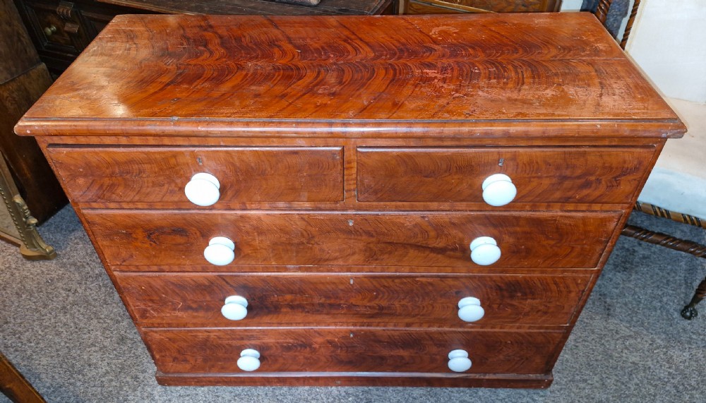 A Victorian pine chest of drawers featuring a warm brown scumbled faux-grain painted finish, two short drawers over three long drawers, and white turned handles. View VI
