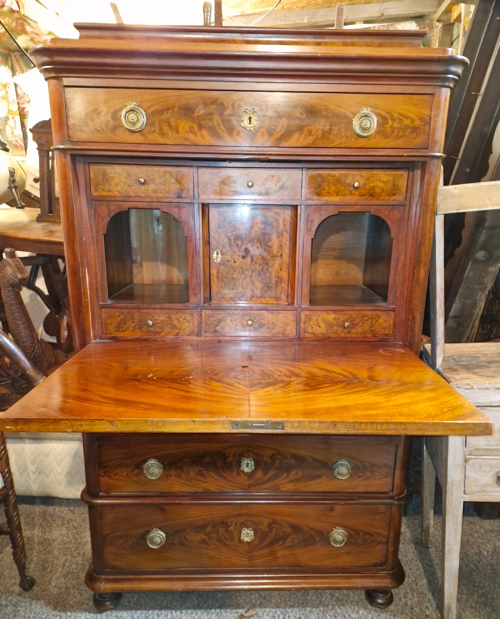 A 19th-century mahogany fall-front escritoire featuring flame mahogany veneer panels, a drop-down writing surface, multiple storage drawers, and brass fittings. View II