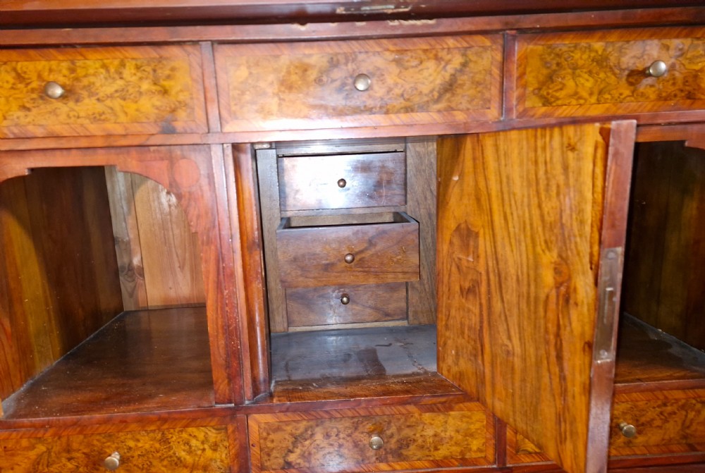 A 19th-century mahogany fall-front escritoire featuring flame mahogany veneer panels, a drop-down writing surface, multiple storage drawers, and brass fittings. View V