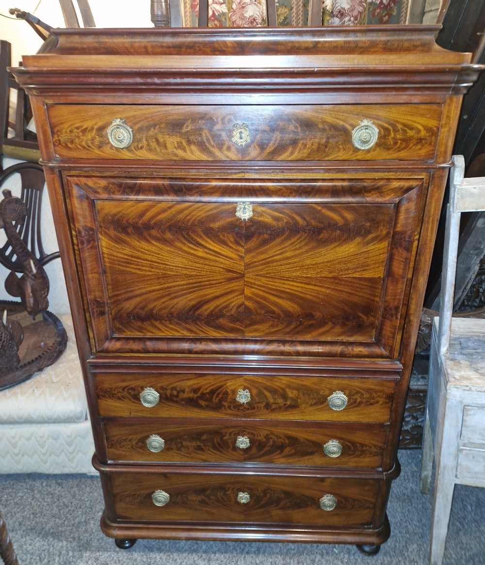 A 19th-century mahogany fall-front escritoire featuring flame mahogany veneer panels, a drop-down writing surface, multiple storage drawers, and brass fittings.