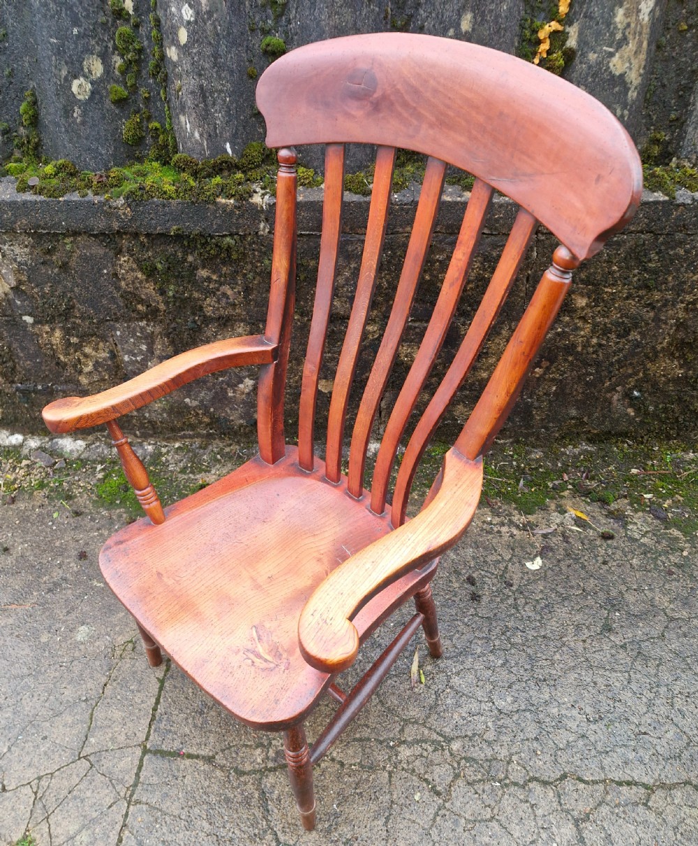 A Victorian wooden slat back Windsor armchair with turned legs, flat armrests, and a shaped saddle seat. View IV