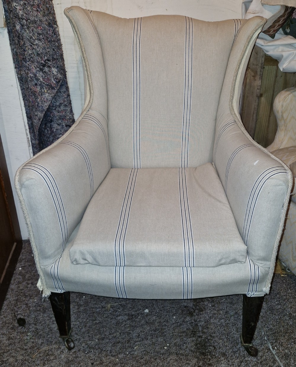 An Edwardian upholstered bedroom armchair covered in beige ticking stripe linen with tapered front legs set on brass castors. View VIII