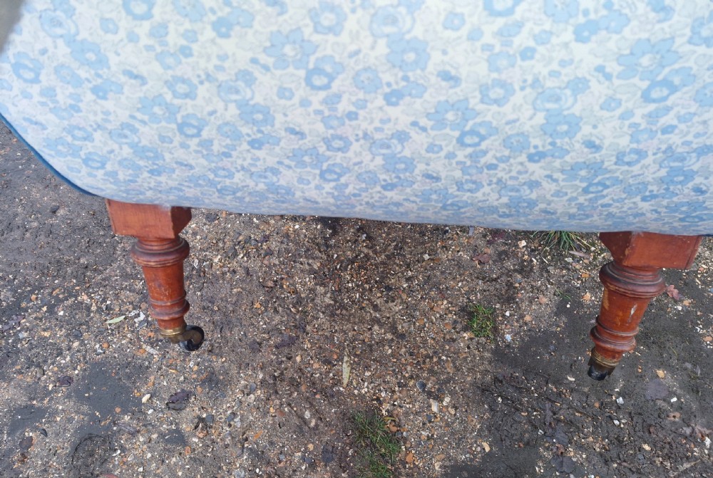 A late Victorian upholstered day bed with an S-shaped contour, blue and white patterned fabric, turned timber legs, and small wheel castors. View II