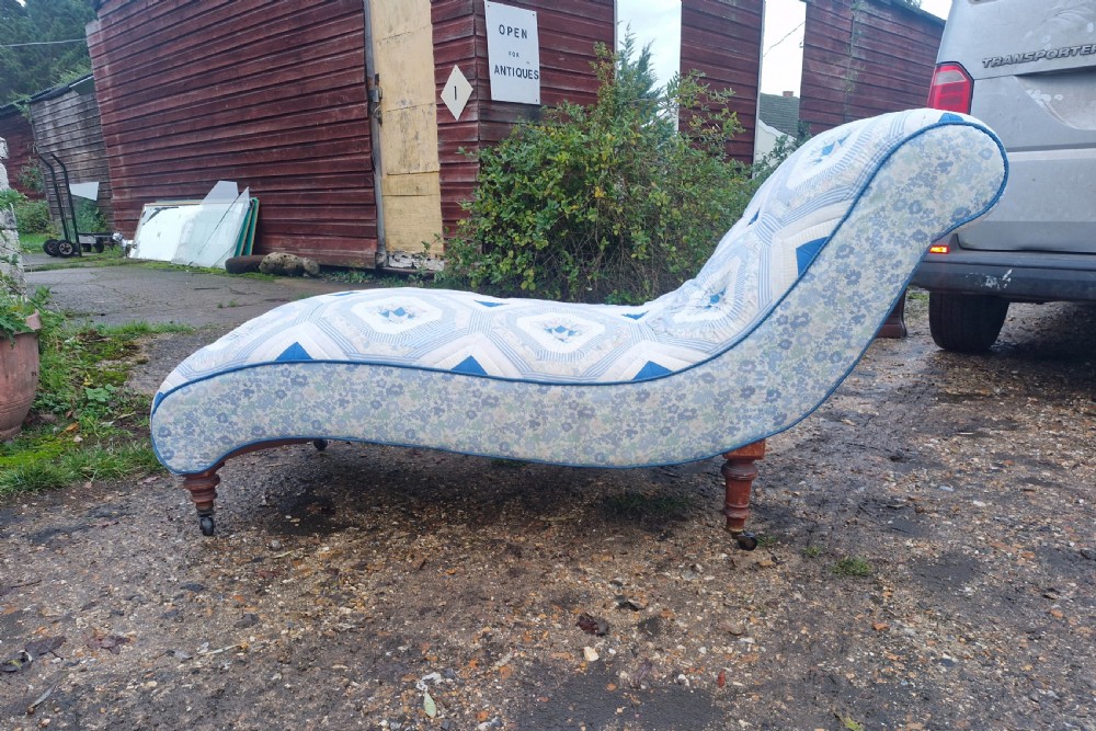 A late Victorian upholstered day bed with an S-shaped contour, blue and white patterned fabric, turned timber legs, and small wheel castors. View VI