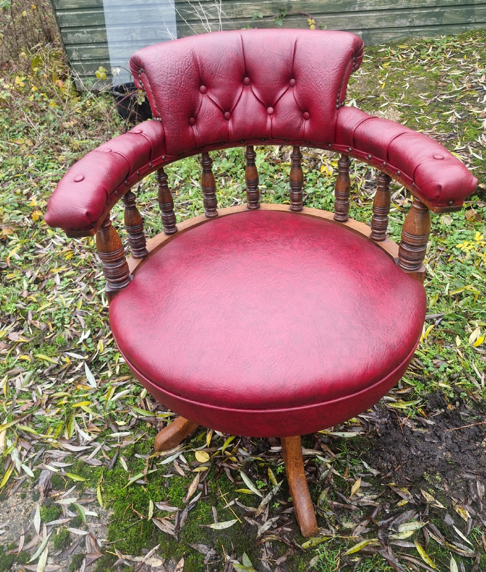 A late Victorian oak revolving desk armchair featuring deep button-tufted red upholstery, turned spindle back supports, and a four-point splayed wooden base. View II
