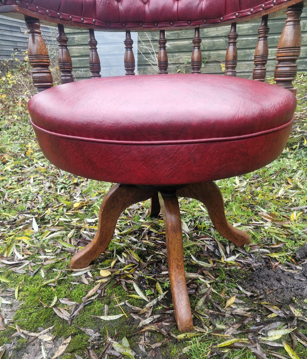 A late Victorian oak revolving desk armchair featuring deep button-tufted red upholstery, turned spindle back supports, and a four-point splayed wooden base. View VI