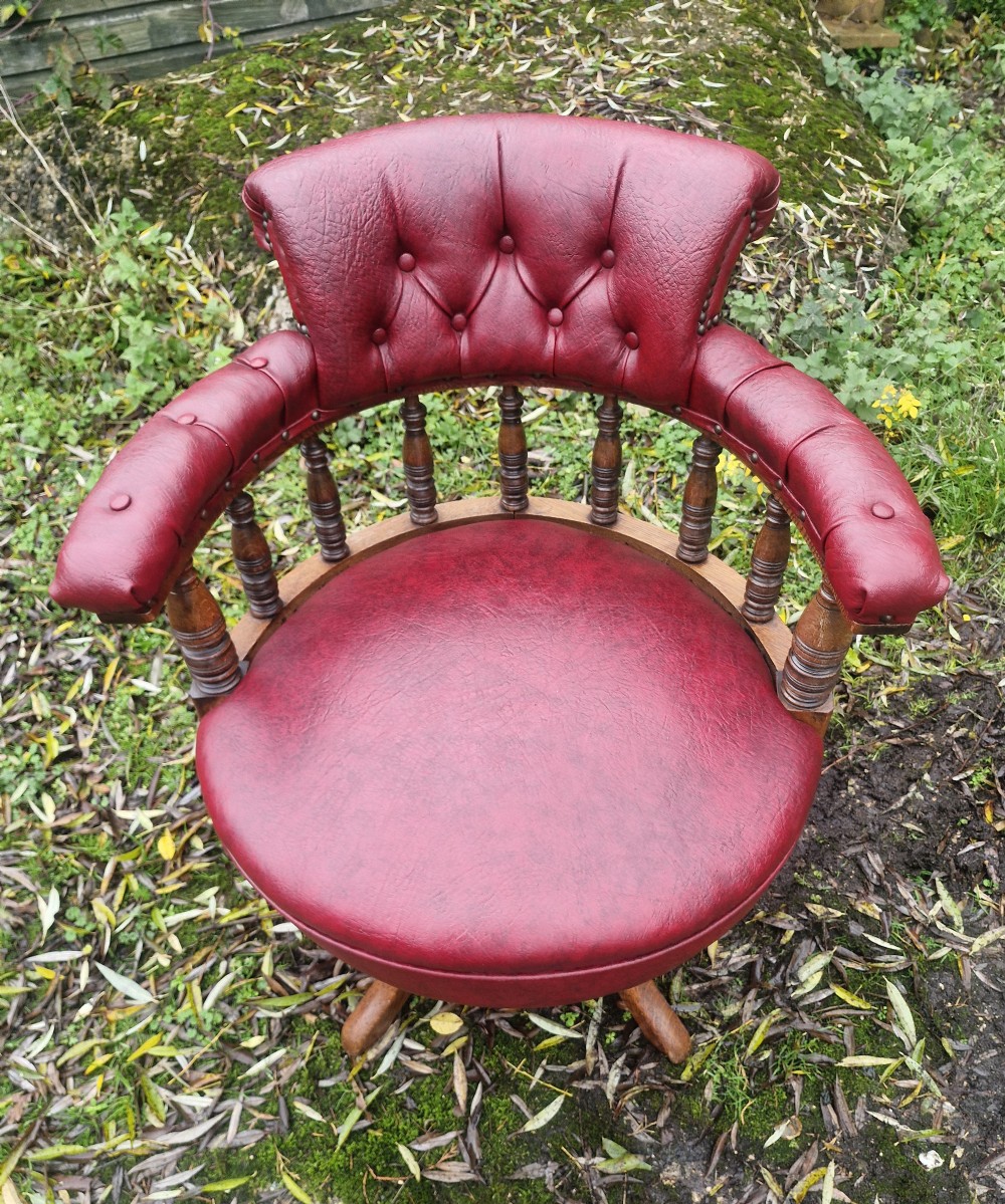 A late Victorian oak revolving desk armchair featuring deep button-tufted red upholstery, turned spindle back supports, and a four-point splayed wooden base. View VIII