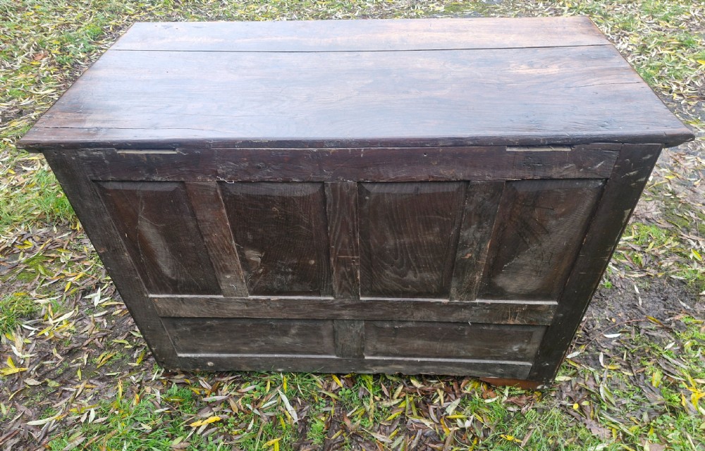 A dark brown Georgian oak chest of drawers featuring geometric moulded drawer fronts and brass drop handles. View VII