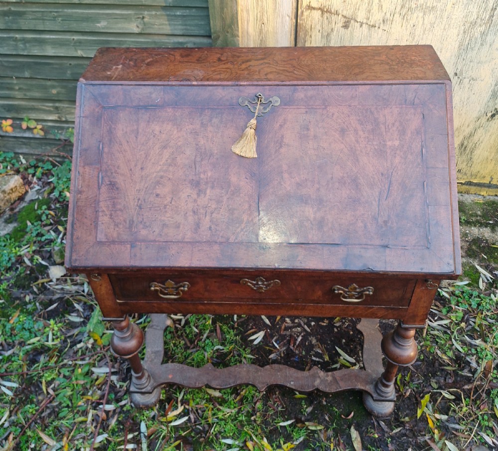 A Queen Anne style burr walnut and burr elm slant-front writing bureau raised on turned legs with a stretcher base.