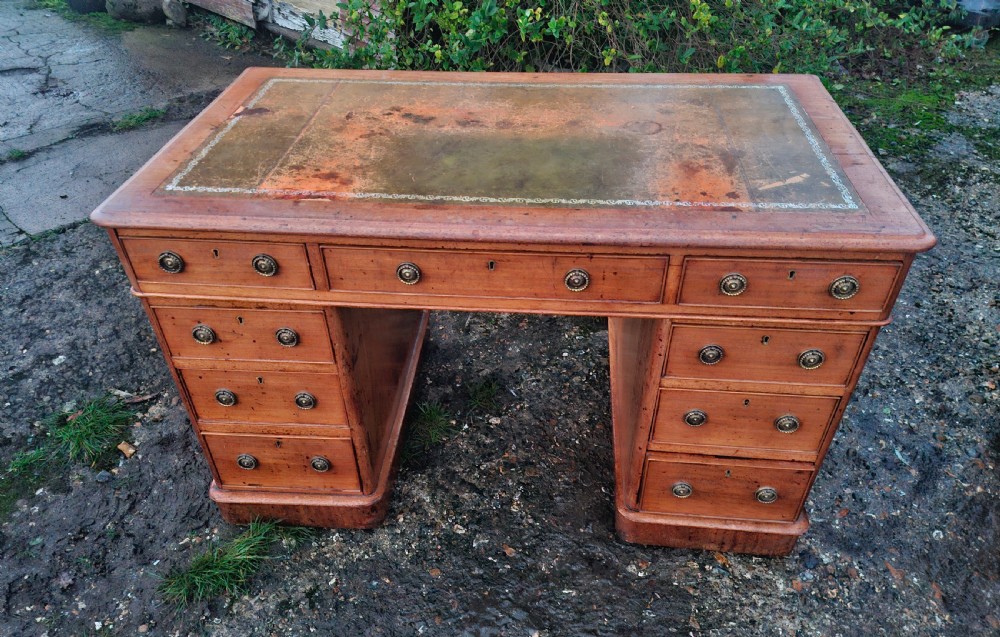 A mid-19th-century mahogany kneehole pedestal desk featuring nine drawers with brass handles and a patinated inset leather writing surface.