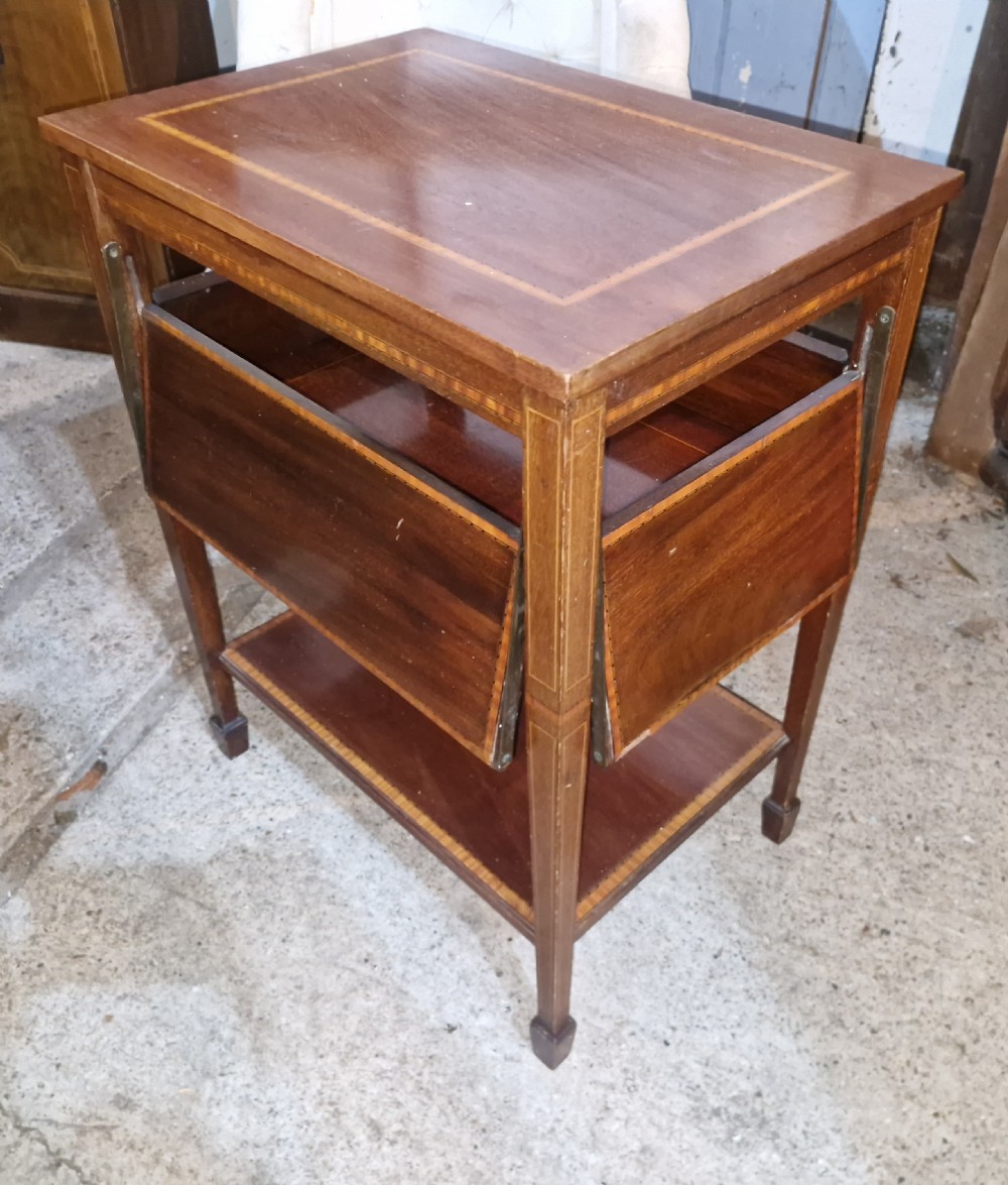 An Edwardian mahogany tea table featuring satinwood string inlay, four drop-down flap leaves, a lower tier shelf, and tapered legs.