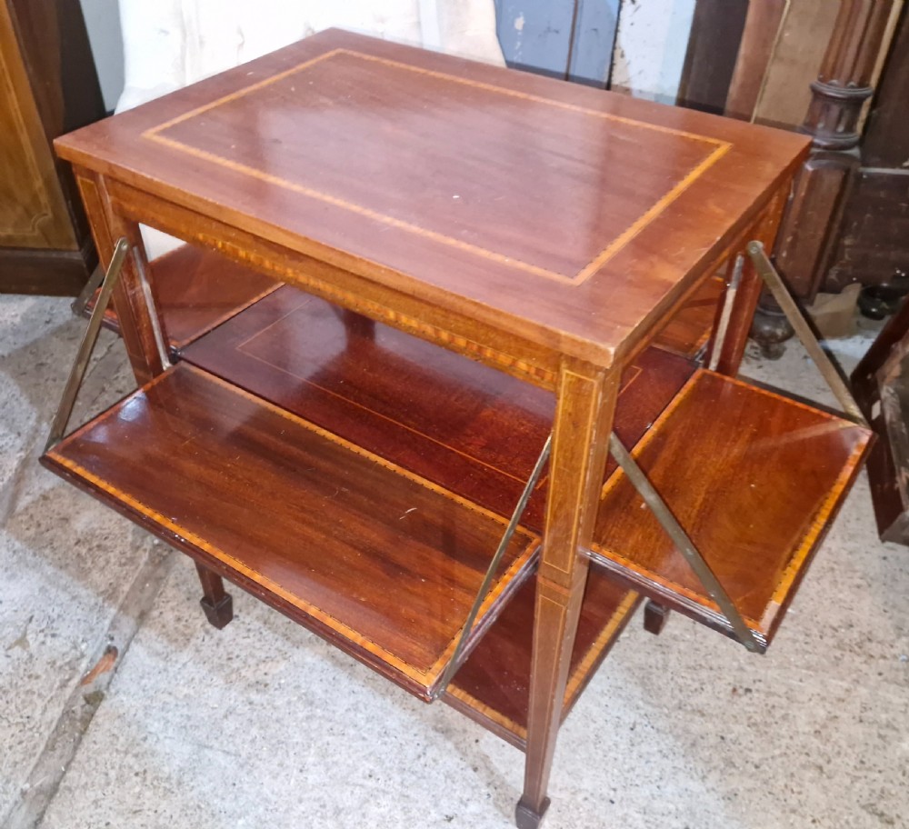 An Edwardian mahogany tea table featuring satinwood string inlay, four drop-down flap leaves, a lower tier shelf, and tapered legs. View II