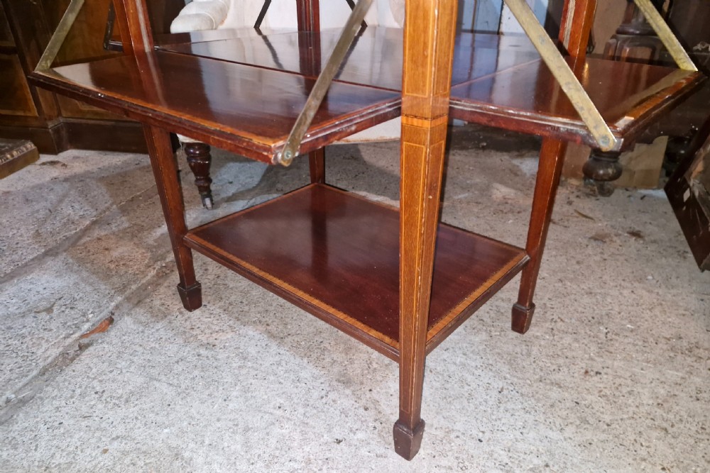 An Edwardian mahogany tea table featuring satinwood string inlay, four drop-down flap leaves, a lower tier shelf, and tapered legs. View III