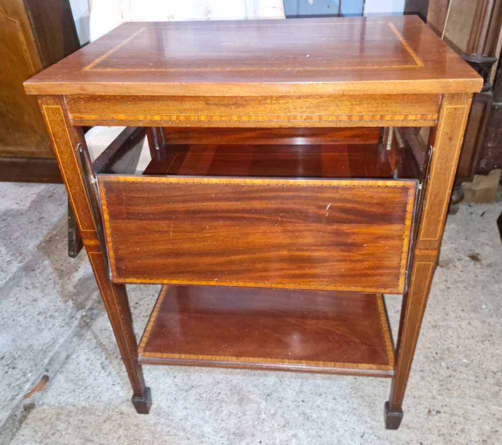 An Edwardian mahogany tea table featuring satinwood string inlay, four drop-down flap leaves, a lower tier shelf, and tapered legs. View V