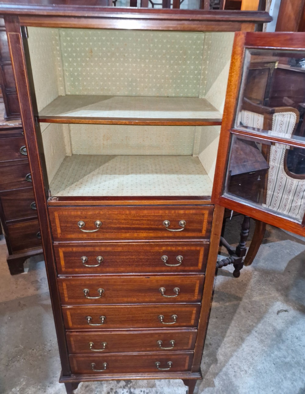 An Edwardian mahogany music cabinet featuring a four-pane glazed upper door above six inlaid drawers with brass drop handles. View III