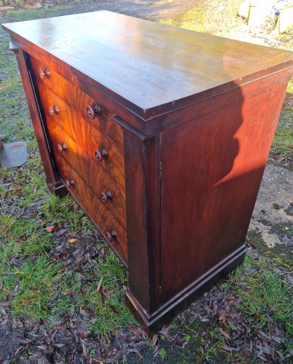 A nineteenth-century Regency chest of drawers featuring four graduated drawers with flame mahogany veneers, turned wooden knobs, and flanking side pilasters. View II