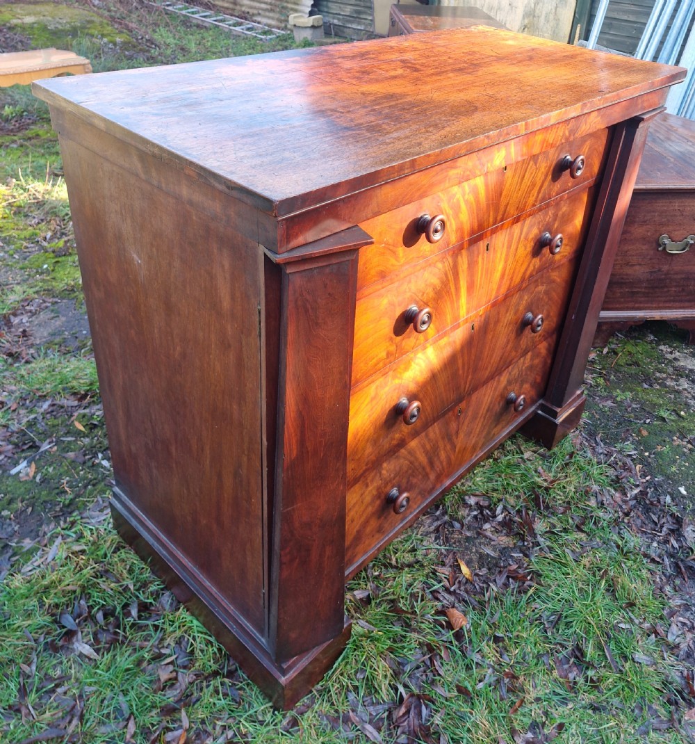 A nineteenth-century Regency chest of drawers featuring four graduated drawers with flame mahogany veneers, turned wooden knobs, and flanking side pilasters. View III