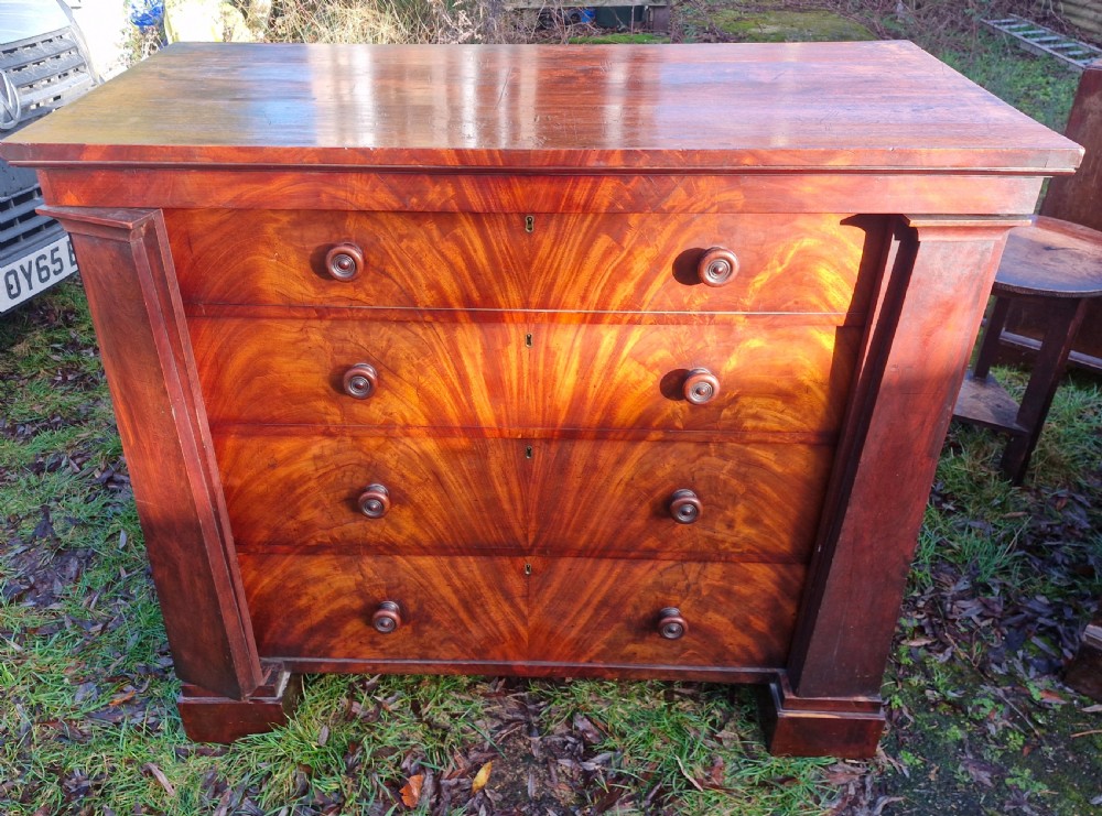 A nineteenth-century Regency chest of drawers featuring four graduated drawers with flame mahogany veneers, turned wooden knobs, and flanking side pilasters. View IX