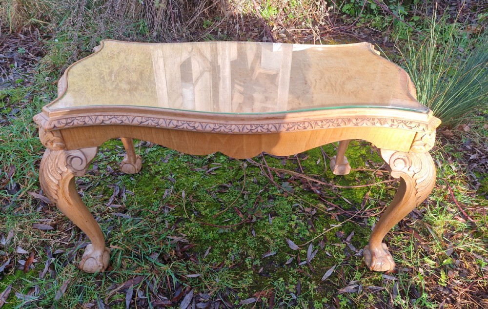 A low rectangular bleached walnut coffee table featuring a glass top insert, carved apron detailing, and cabriole legs.