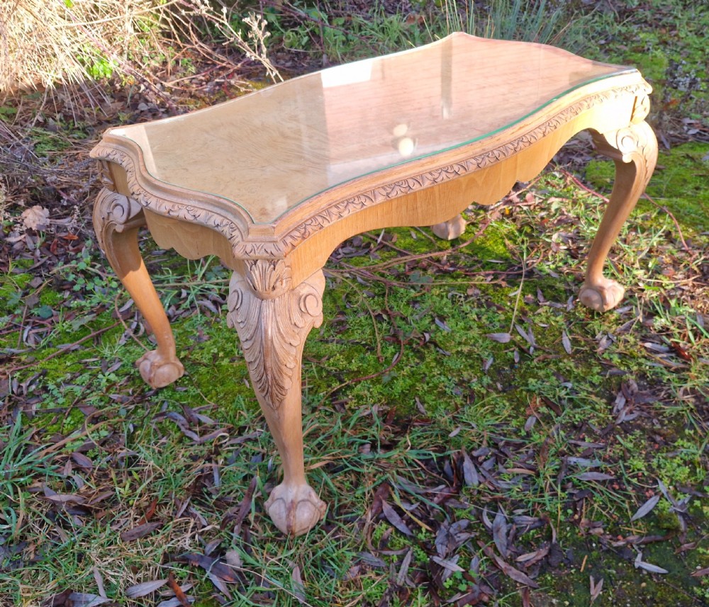 A low rectangular bleached walnut coffee table featuring a glass top insert, carved apron detailing, and cabriole legs. View V