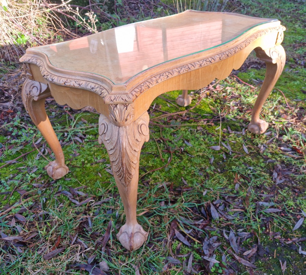 A low rectangular bleached walnut coffee table featuring a glass top insert, carved apron detailing, and cabriole legs. View VI